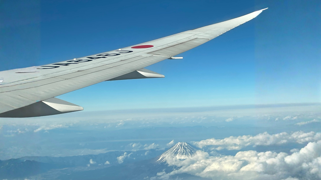 飛行機の窓から見える翼と雲の上の富士山