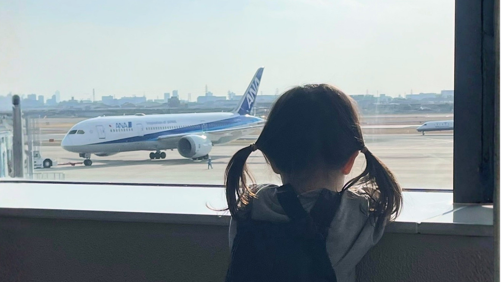 空港の窓からANAの飛行機を眺める子ども